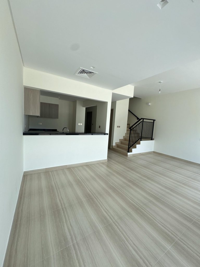 Empty contemporary living space with open kitchen and stairs.